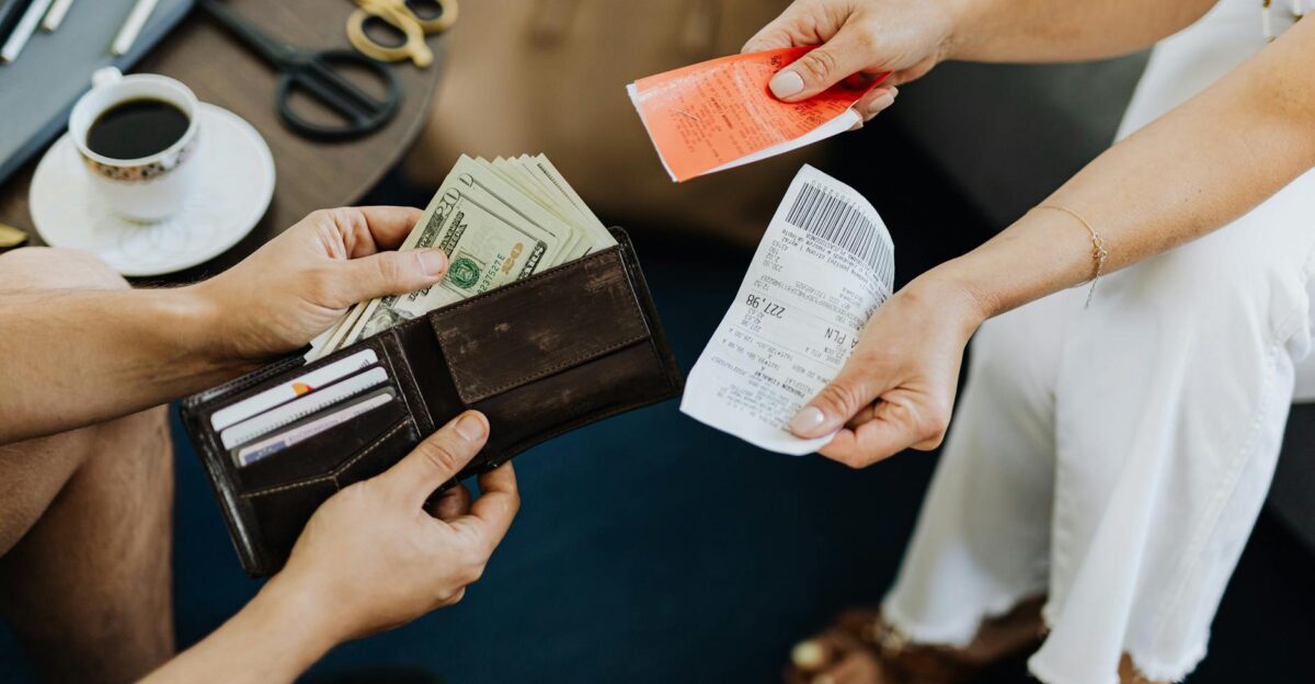 Close-up of a financial transaction involving cash and receipts over a coffee table