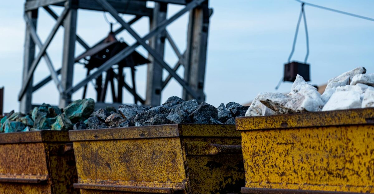 Detailed view of rusty mining equipment loaded with rocks under a clear sky