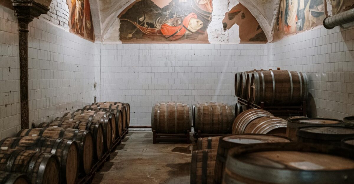 Aged wooden barrels in a historic cellar with decorative murals