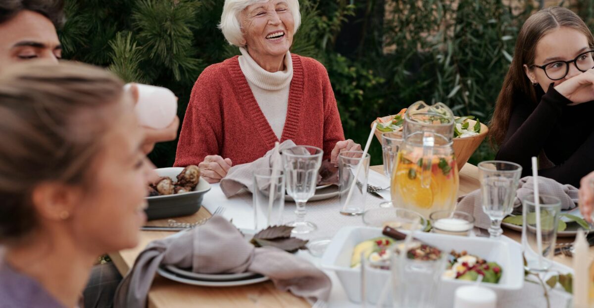 Smiling elderly woman with family and friends enjoying dinner at table backyard garden