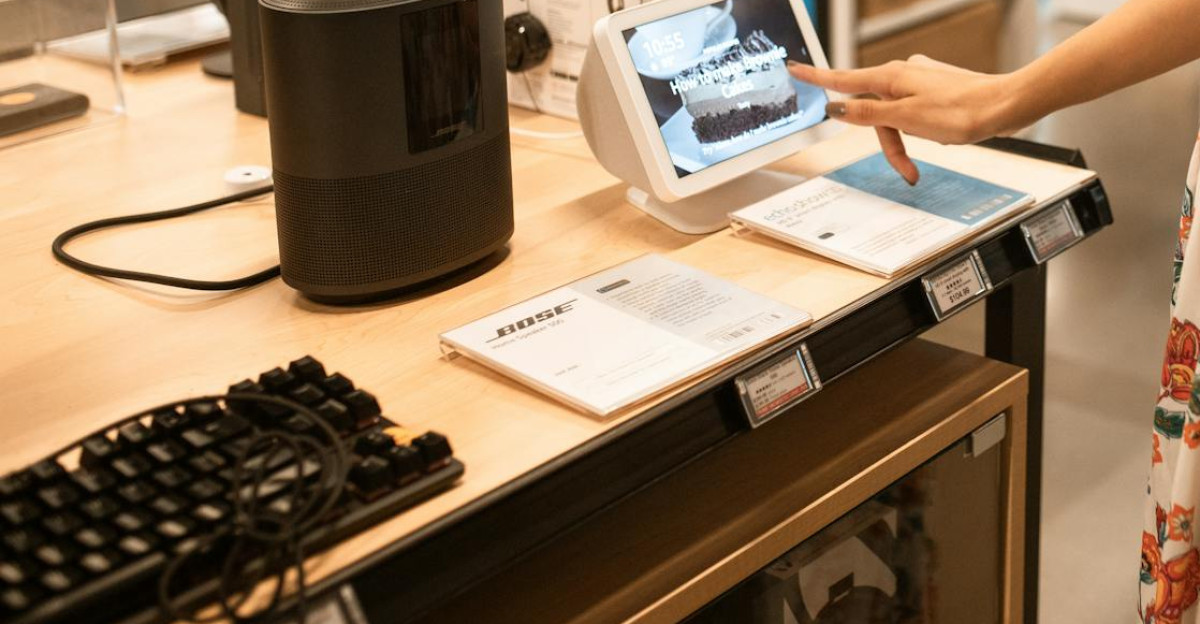 A woman interacts with a touchscreen display in an electronics store while shopping