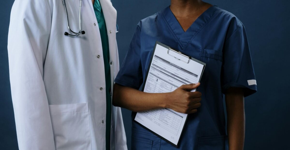 Two healthcare professionals in scrubs and lab coat with a clipboard representing teamwork