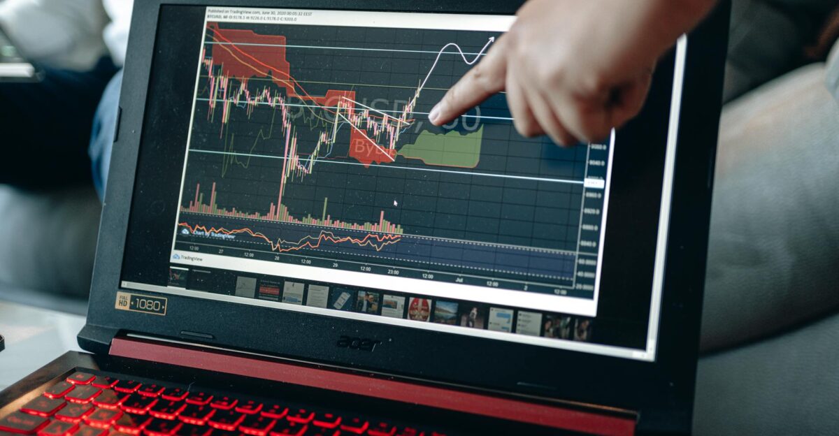 A person points at graph on laptop analyzing stock trends for investment insights