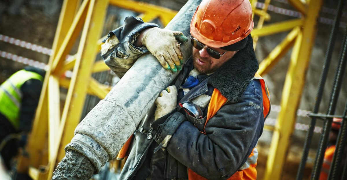 Construction worker in safety gear handling equipment on an active site