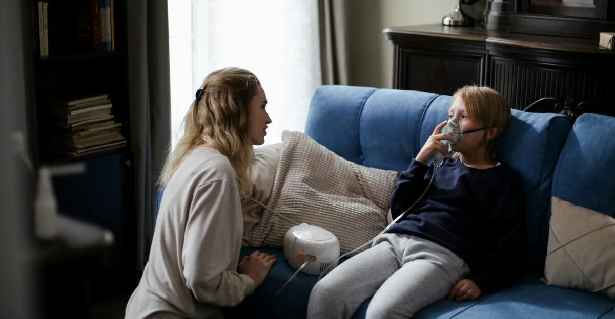 A mother assists her sick child using a nebulizer at home providing comfort and care