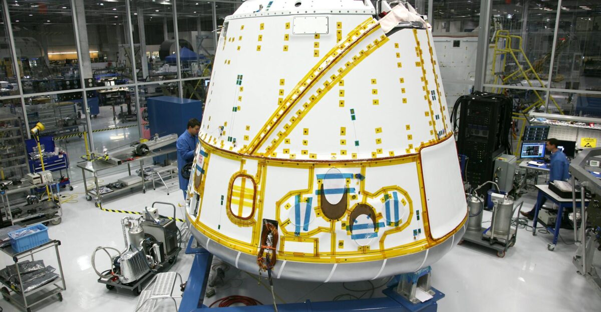 Anonymous male mechanic in uniform fixing detail of spacecraft while working at modern headquarter of industrial factory