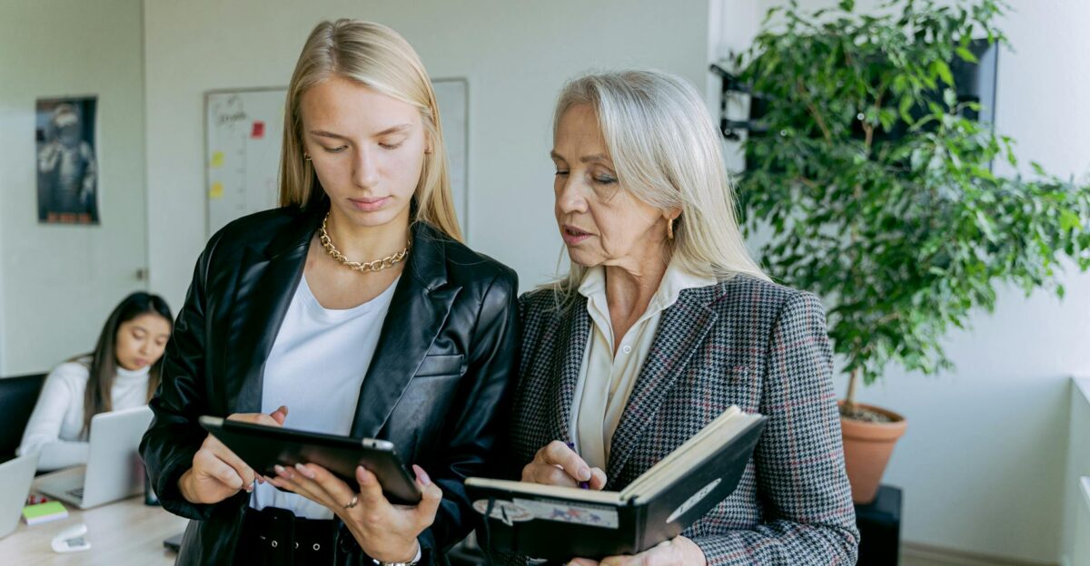 Professional women discussing work in a modern office setting with colleagues