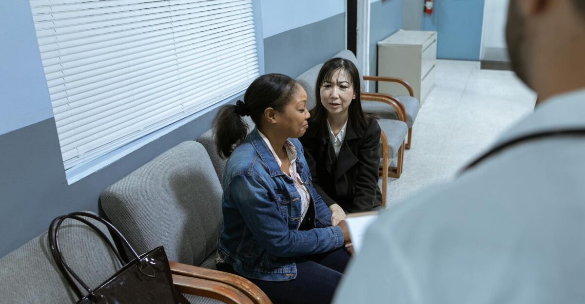 Two women in a clinic waiting room speaking with a doctor showcasing healthcare interaction