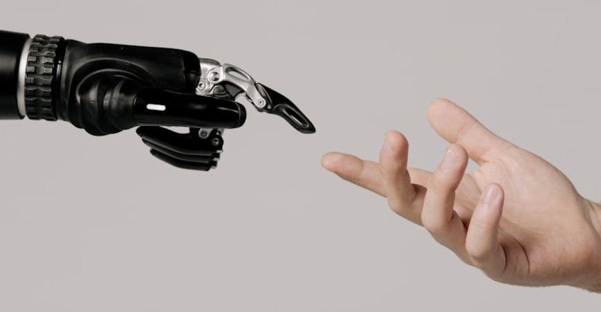 A human hand reaching to touch a bionic prosthetic hand on a white background