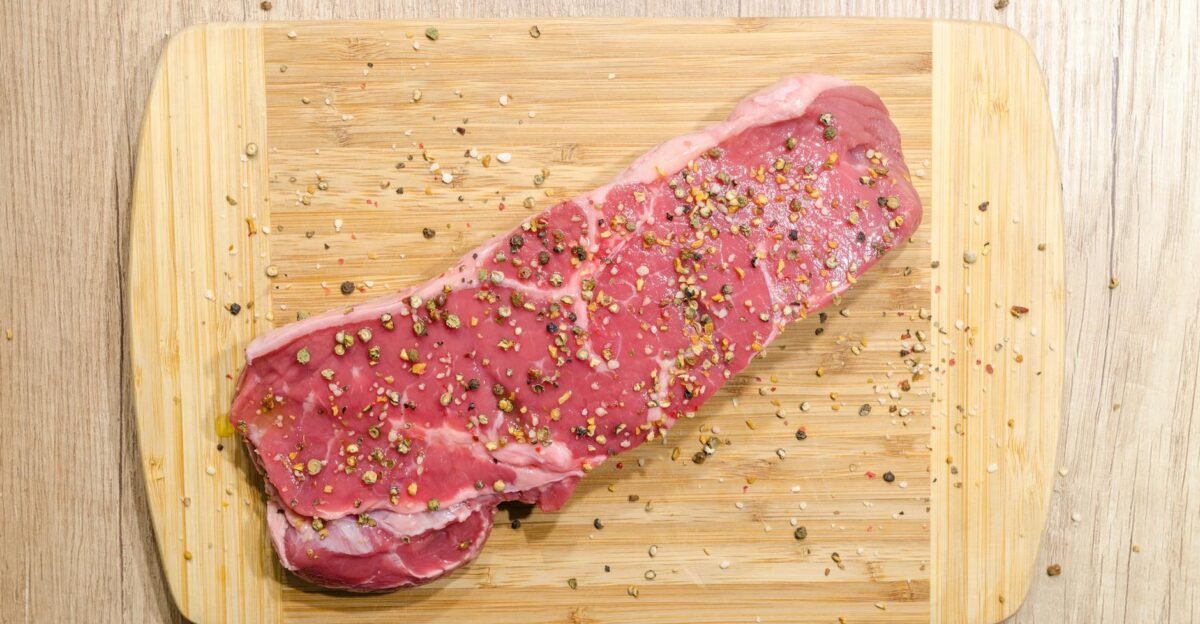 Raw beef steak seasoned with spices on a wooden chopping board Perfect for cooking enthusiasts