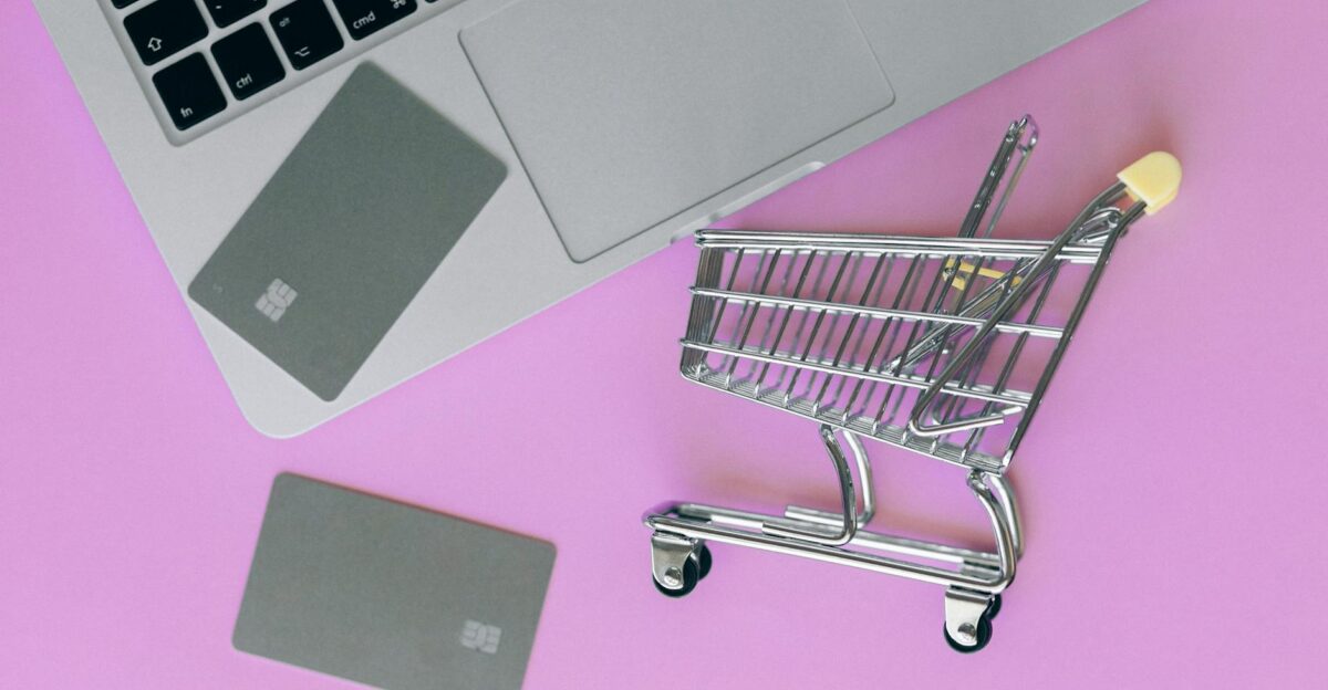 A minimalist flat lay of a credit card laptop and miniature shopping cart