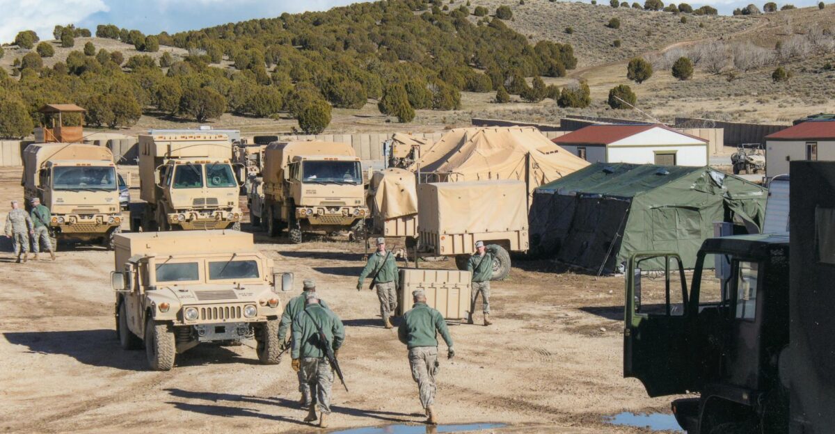 Military vehicles and tents at a training camp in Afghanistan under clear skies