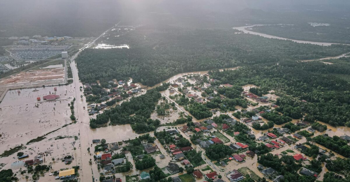 Aerial view of many residential houses and lush green trees in flooded small city