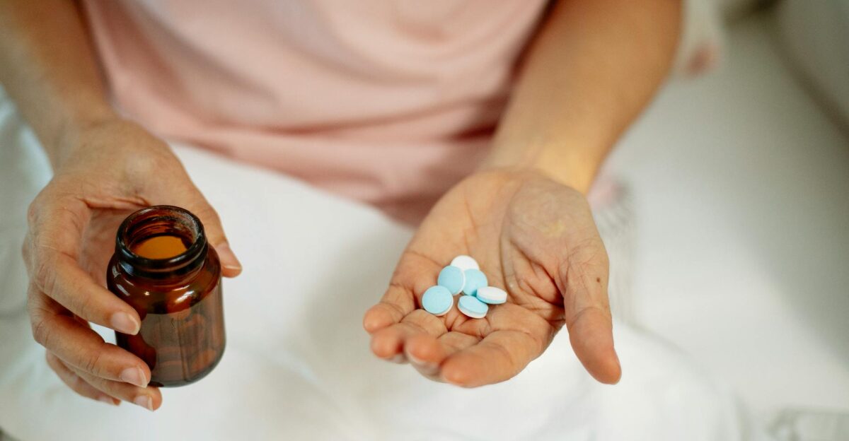 Close-up of an adult taking medication with blue pills in hand promoting health recovery at home