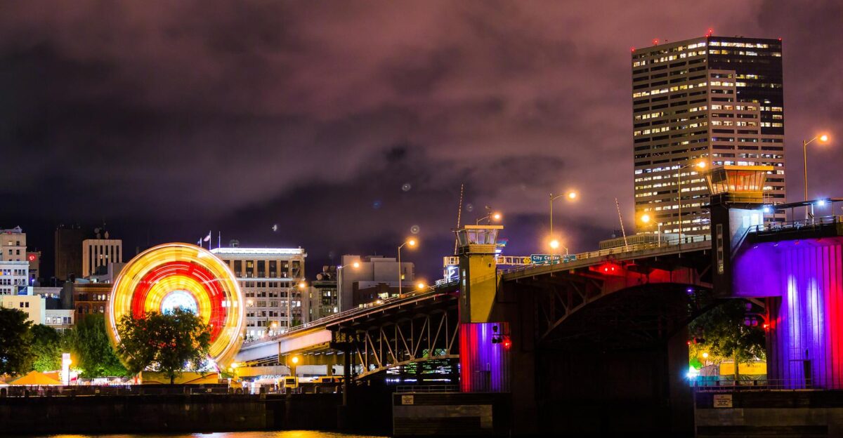 A night view of Portland s illuminated skyline featuring a ferris wheel and bridge reflection on the waterfront