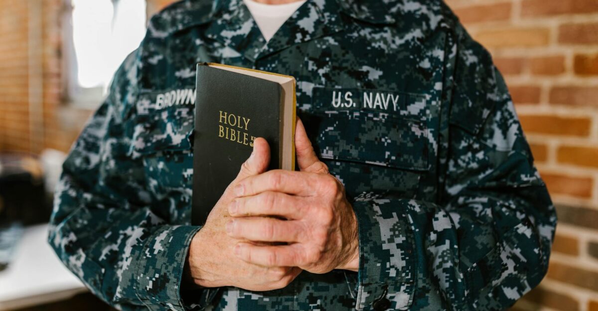 A U S Navy sailor in uniform holding a Holy Bible symbolizing faith and service