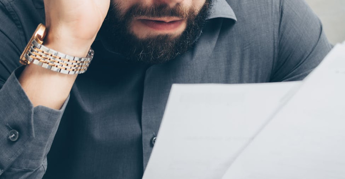 Man with glasses scrutinizing financial papers showing concern