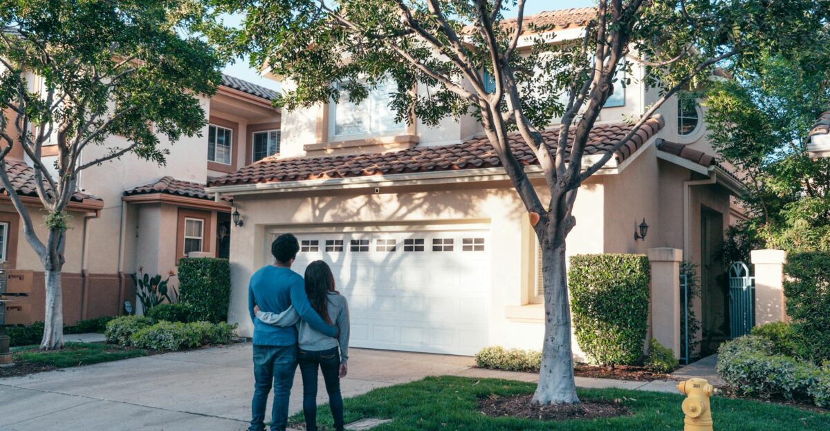 Couple hugging outside their newly purchased suburban home showcasing togetherness and new beginnings