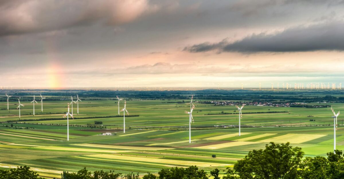 Beautiful aerial view of a wind farm in a lush countryside with a rainbow on the horizon showcasing renewable energy and nature
