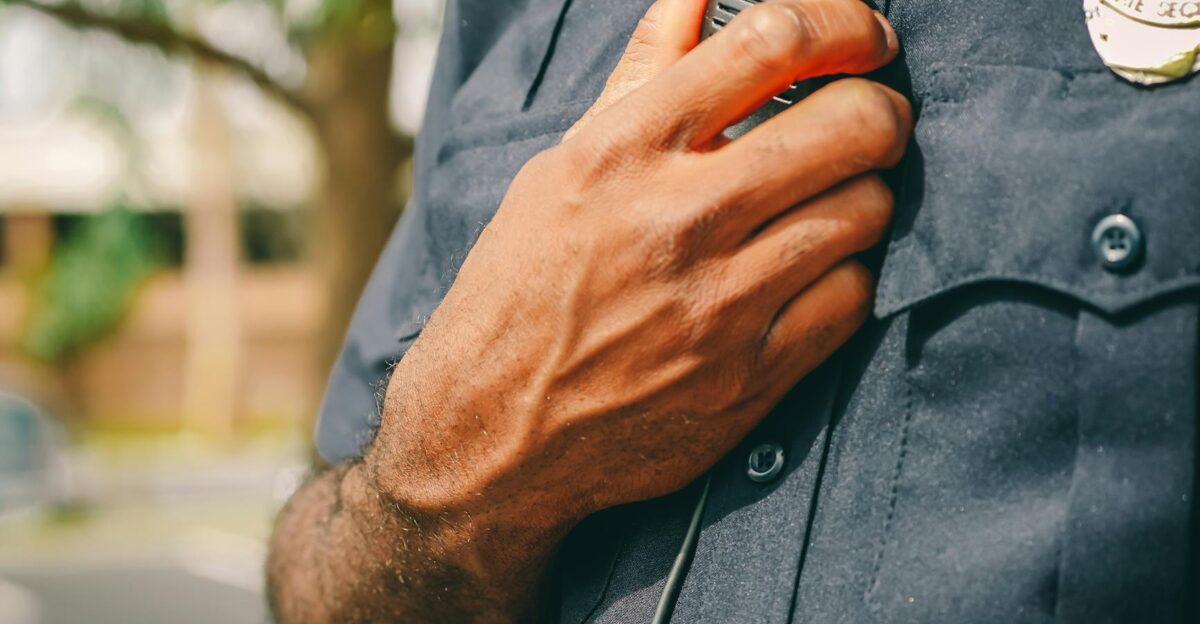Close-up of police officer holding a radio outdoors showcasing communication tools in law enforcement