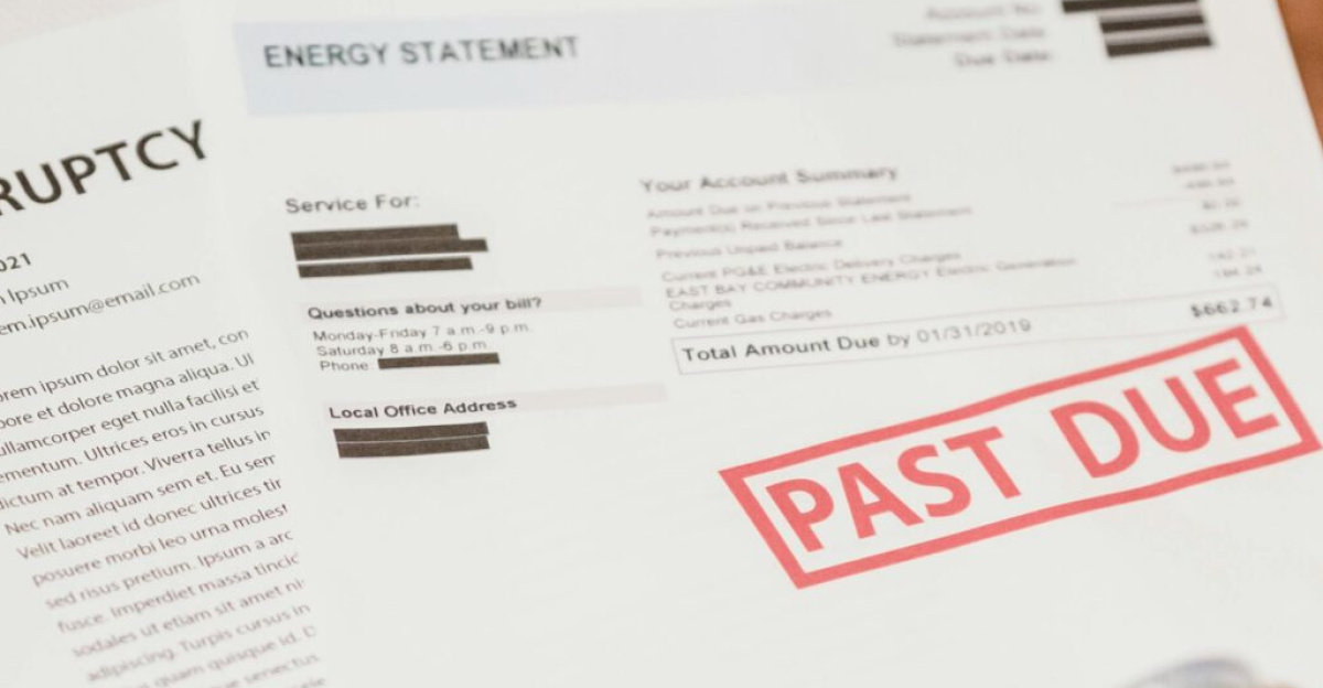 Man holding bills labeled 'Past Due' and a drink can, lying on a sofa.