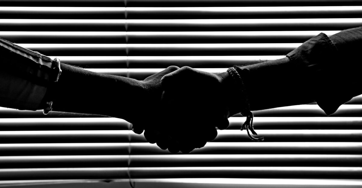 Silhouette of two people shaking hands symbolizing partnership and trust