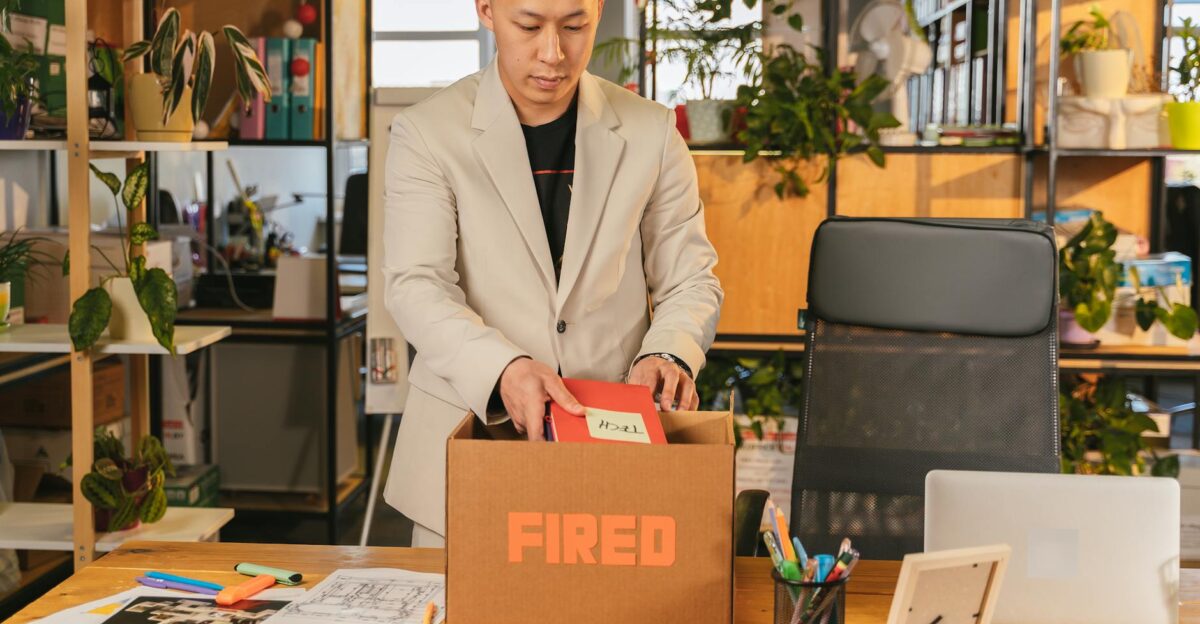 An adult man pack personal items after receiving a fired notice in an office setting expressing corporate life challenges
