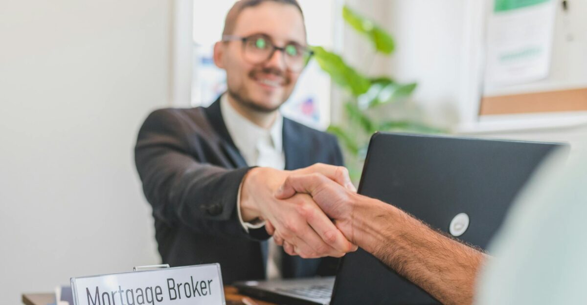 Mortgage broker and client sealing a deal with a handshake in a bright modern office