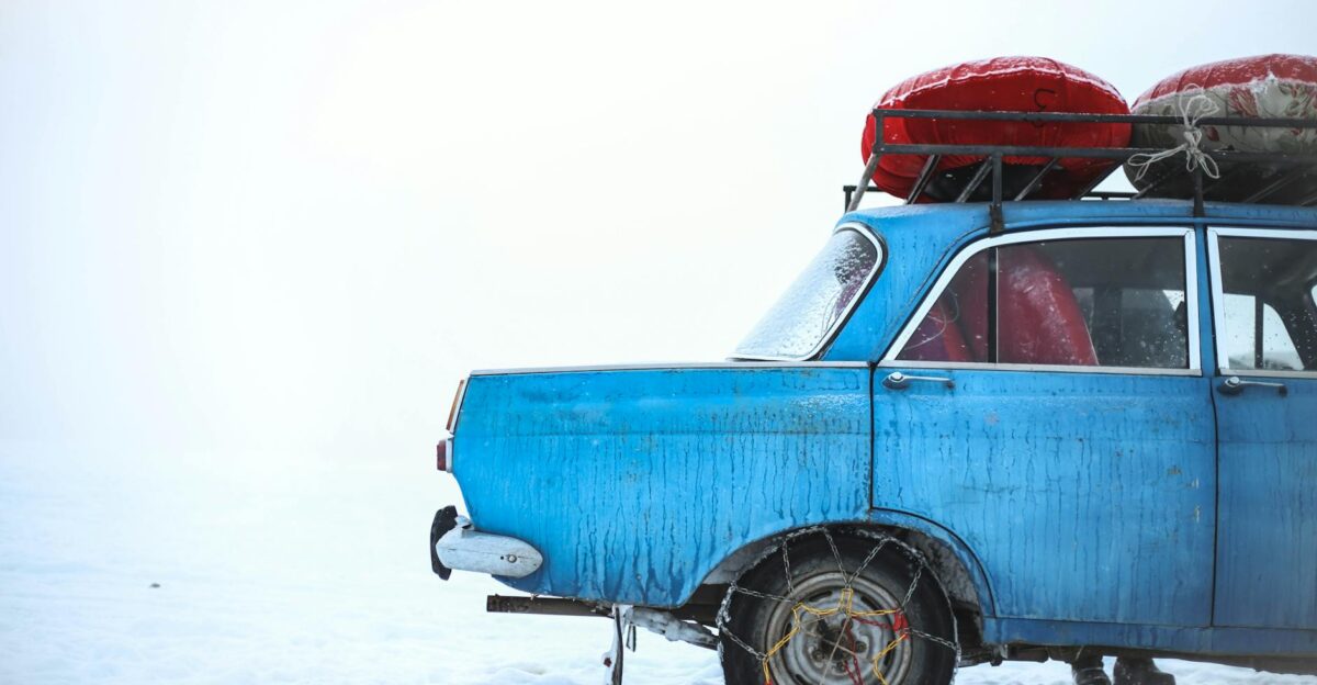 A vintage blue car with roof luggage in snowy Ak-Talaa Kyrgyzstan