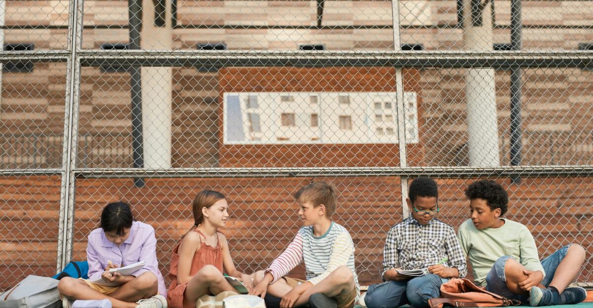 A group of teenagers studying collaboratively on an outdoor sports ground