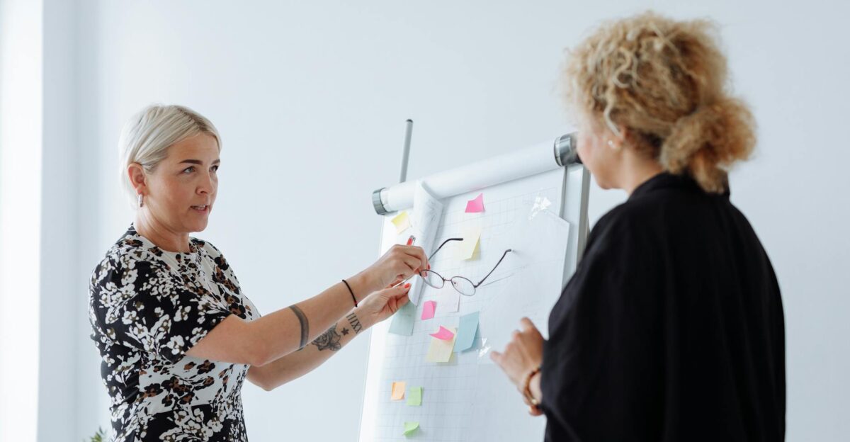 Two professional women discussing ideas at a business meeting using a flip chart