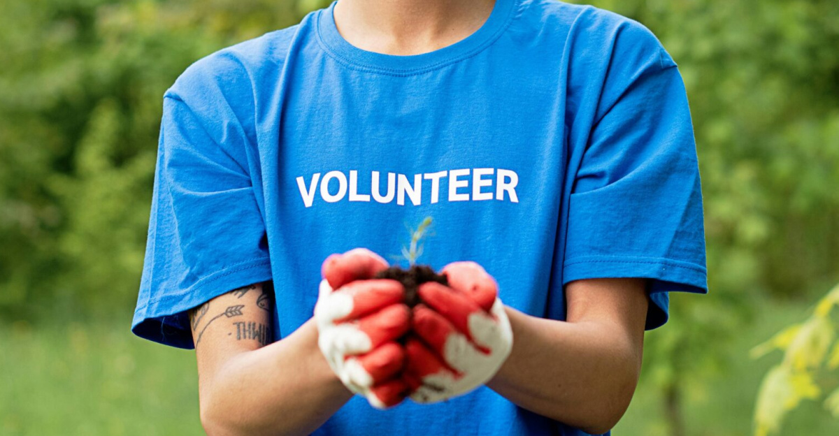 A young male volunteer holding a seedling, promoting environmental conservation.