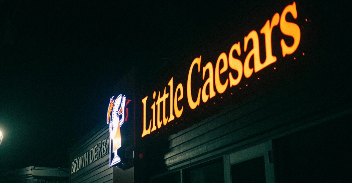 A dimly lit image of a Little Caesars restaurant sign glowing in the night