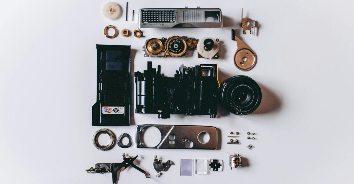 Flat lay of various disassembled camera parts on a white surface showcasing intricate details