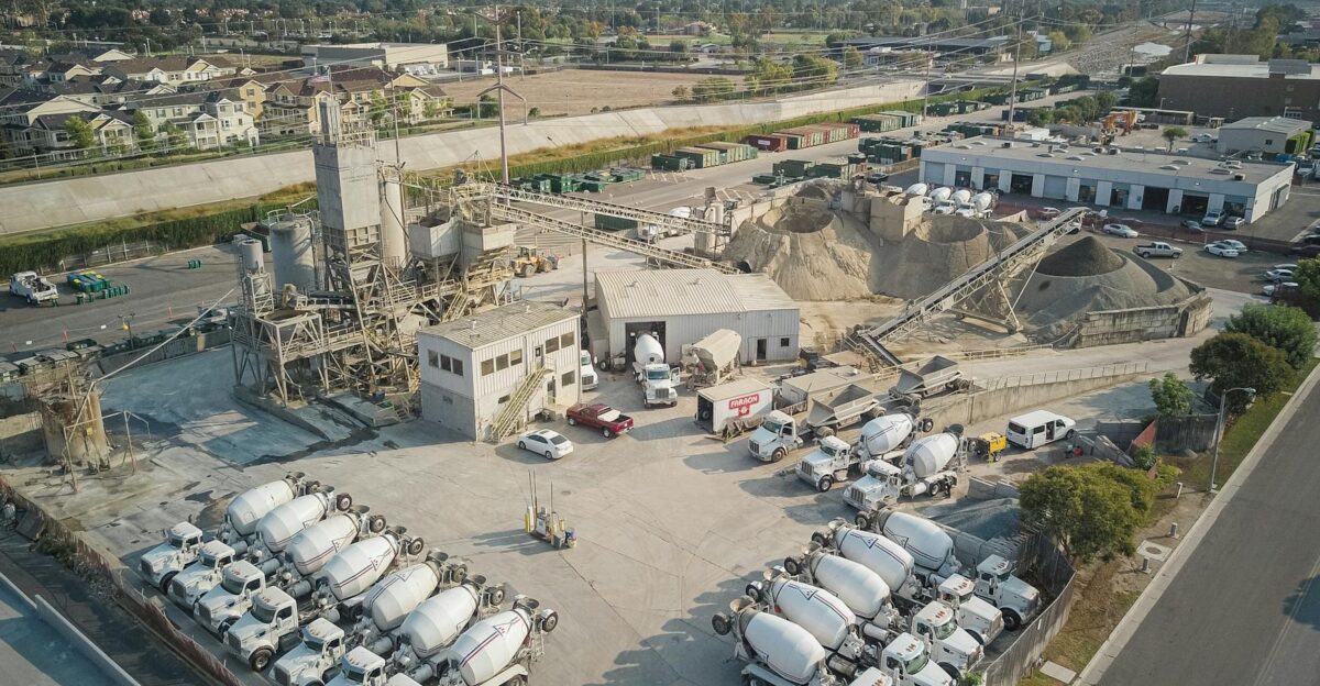 Aerial shot of a bustling cement manufacturing plant with mixer trucks and industrial equipment