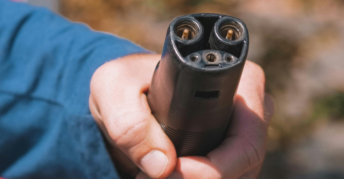 Close-up shot of a hand holding an electric vehicle charger, symbolizing clean energy.