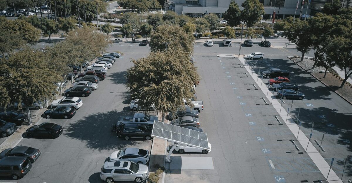 High-angle view of a parking lot with solar panels and parked vehicles surrounded by greenery