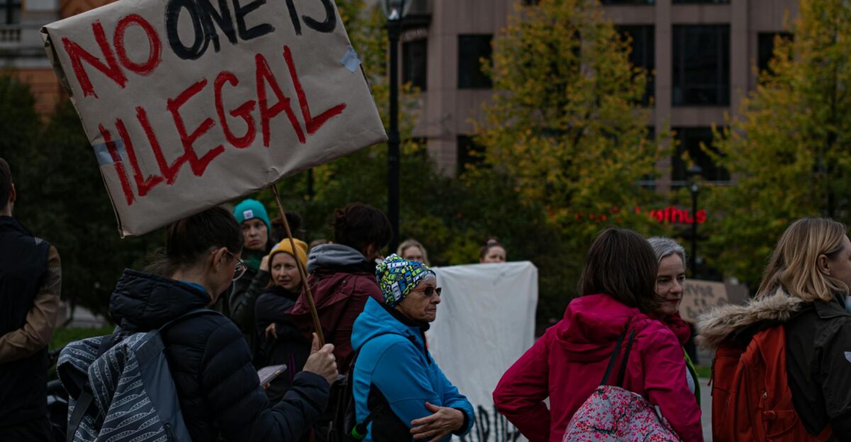 A group of diverse adults protesting immigration policies with signs outdoors