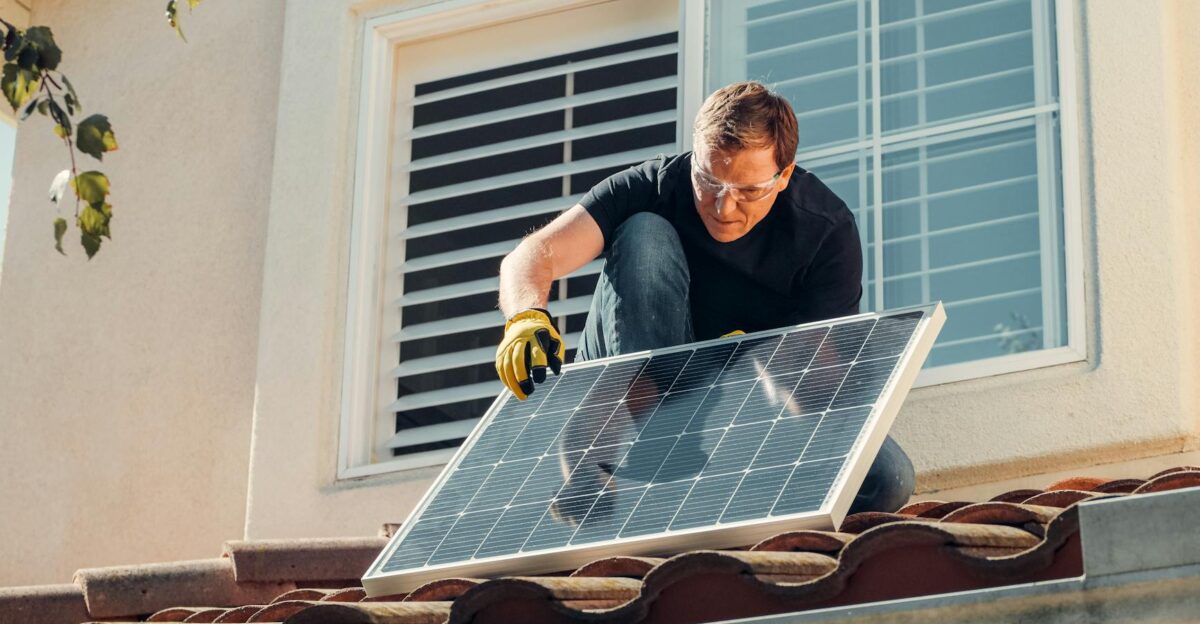 Solar technician installing a photovoltaic panel on a rooftop promoting renewable energy