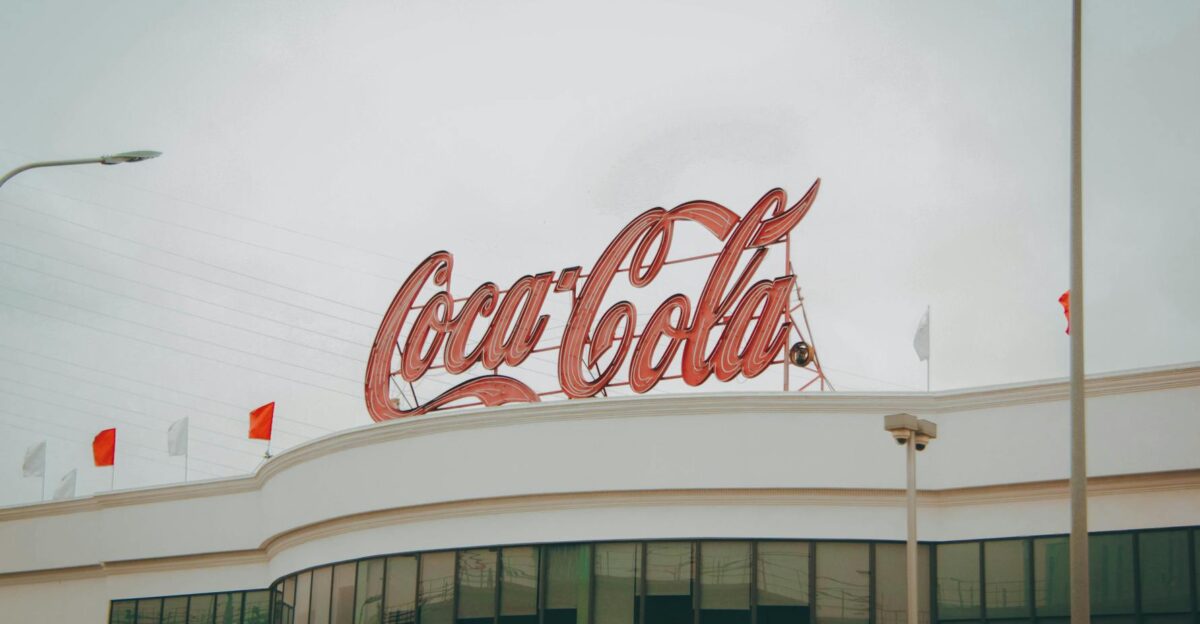 Exterior view of Coca-Cola factory with iconic red sign atop the modern building