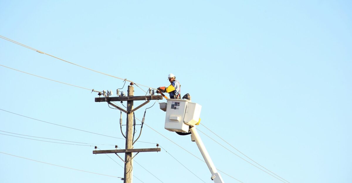 man standing on bucket beside gray current post at daytime