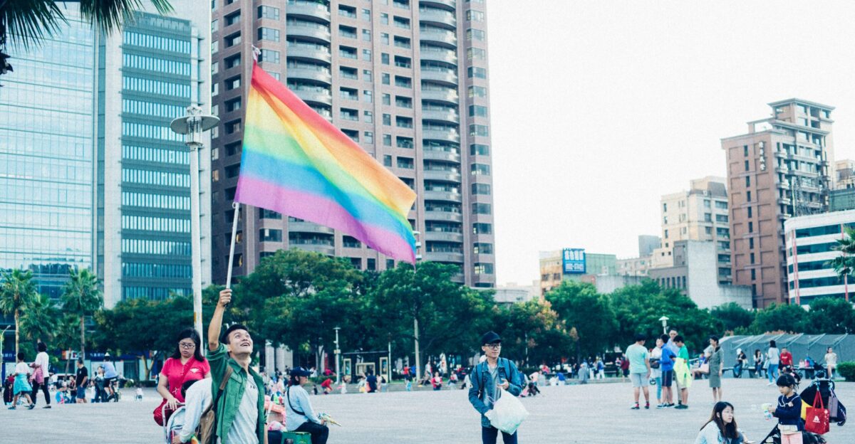 man standing while holding flag near building during daytime