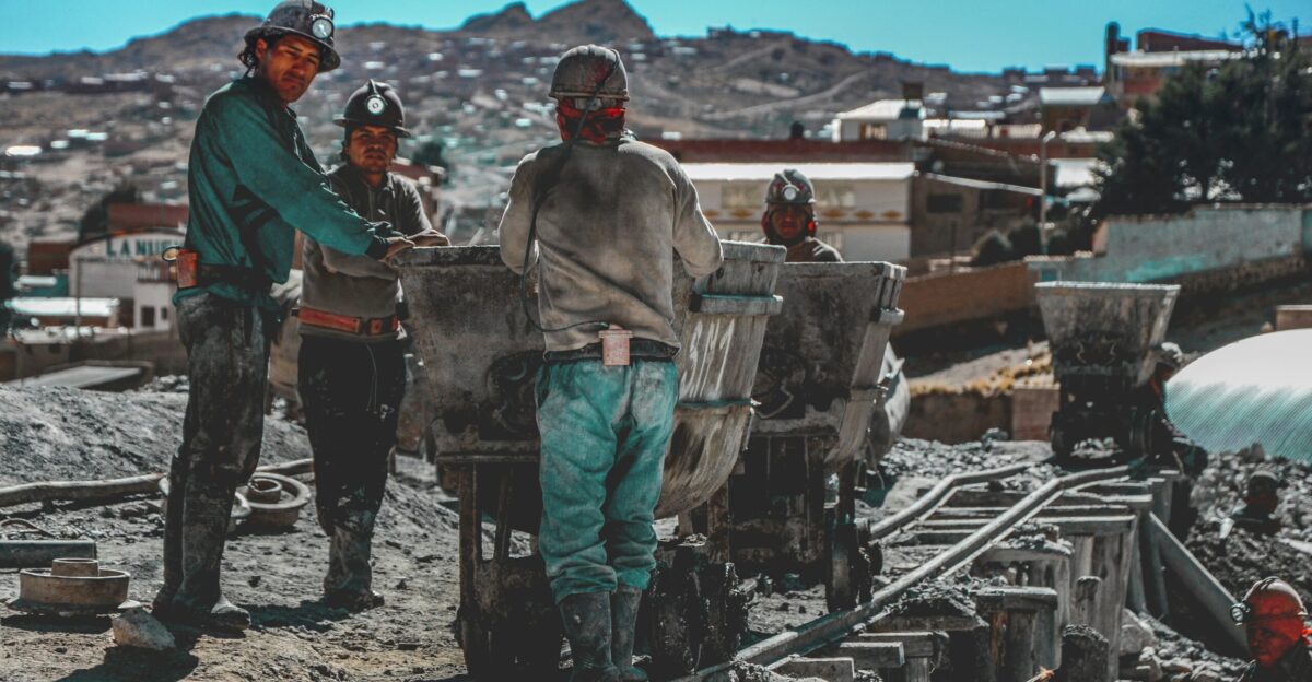 construction workers standing near wheelbarrows near mountain