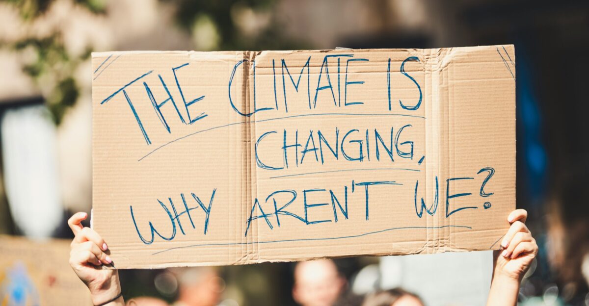 a group of people holding a sign that says the climate is changing why aren
