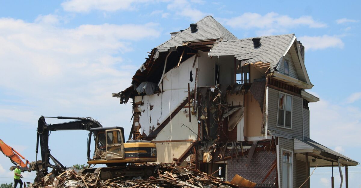 yellow and black heavy equipment near white and brown house during daytime