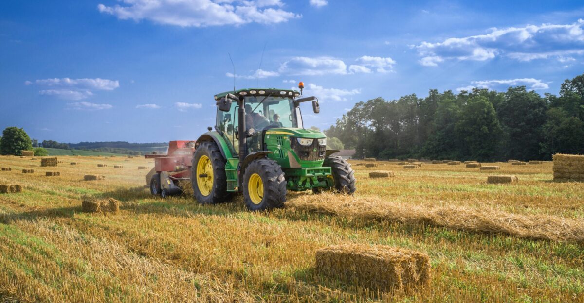 green tractor on brown grass field under blue sky during daytime