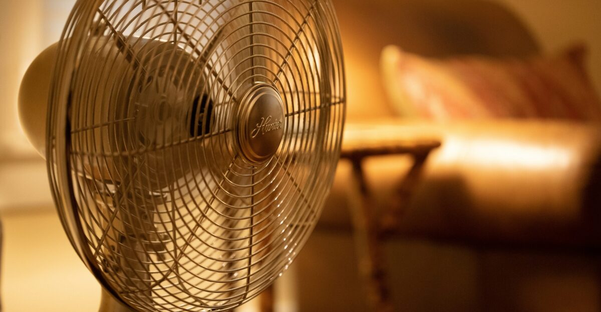 white stand fan turned on in room