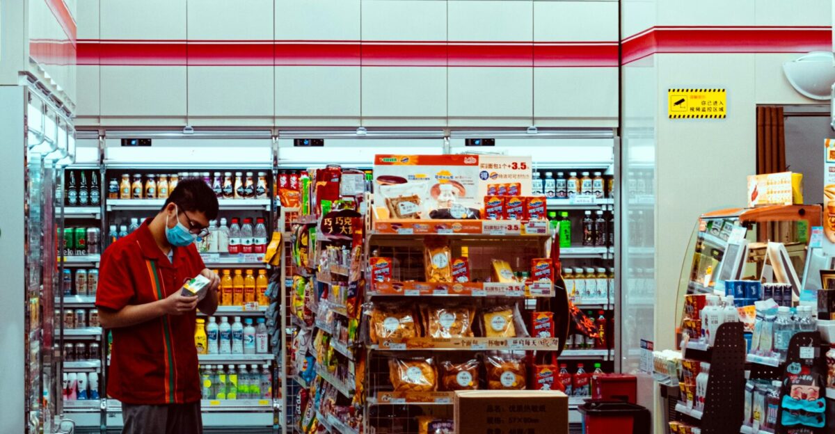 man in red t-shirt standing in front of food stall