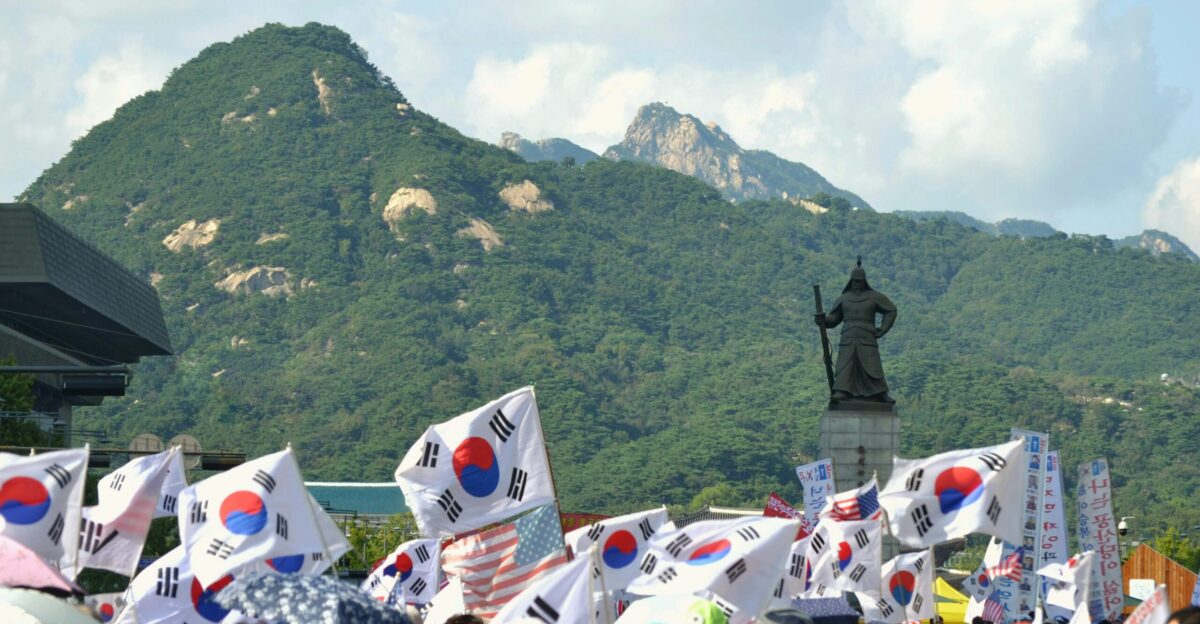 people sitting on white chairs near green mountain during daytime