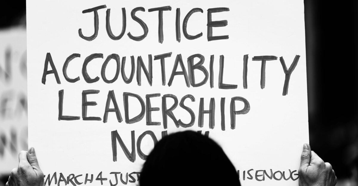 a person holding a sign that says justice acconttability leads to no